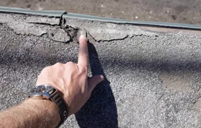 hand pointing to damage on a roof